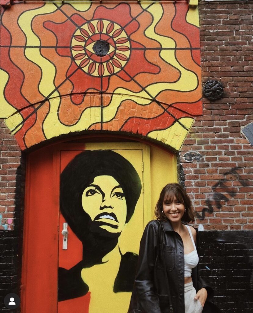 This is a beautiful photo of a beautiful young woman standing in front of the Nina Simone mural.